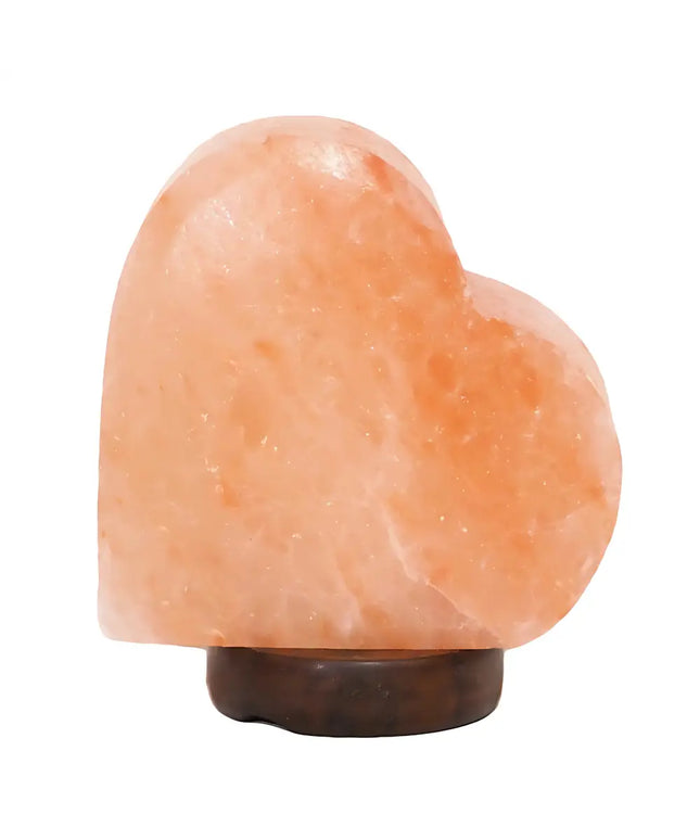 Sideways heart-shaped Himalayan salt lamp on a timber base, glowing softly in a romantic setting.