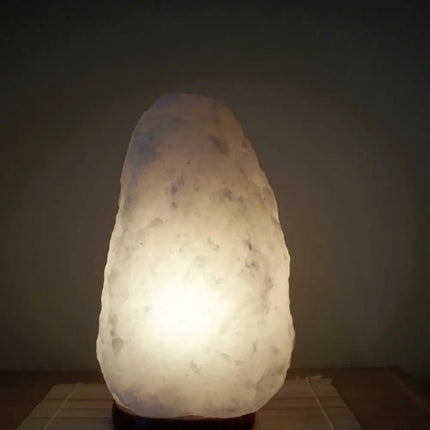 2-3kg white Himalayan salt lamp with a natural timber base emitting a soft glow.