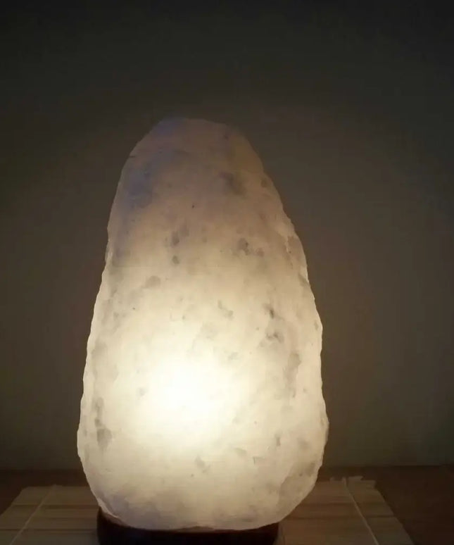 2-3kg white Himalayan salt lamp with a natural timber base emitting a soft glow.