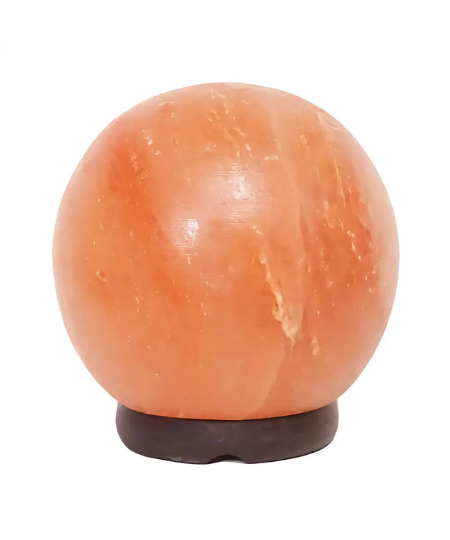 6-inch sphere Himalayan salt lamp on a timber base glowing warmly in a serene bedroom.