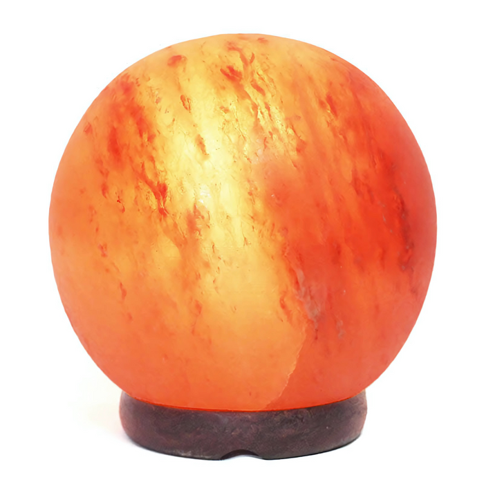 Hand-crafted sphere salt lamp showcasing natural pink hues on a wooden table.