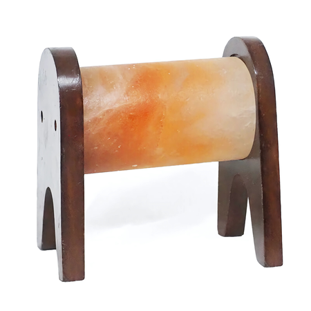 Horizontal cylinder Himalayan salt lamp glowing warmly on a sturdy wooden stand.