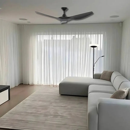 Modern living room with a ceiling fan, gray sectional sofa, and large windows.