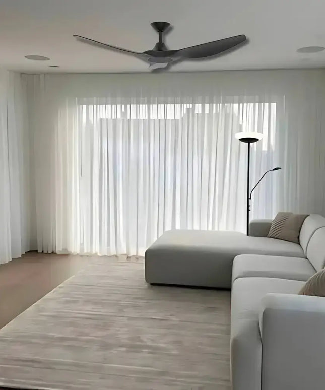 Modern living room with a ceiling fan, gray sectional sofa, and large windows.