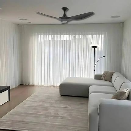 Modern living room with a ceiling fan, gray sectional sofa, and large windows.