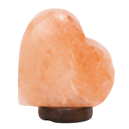 Sideways heart-shaped Himalayan salt lamp on a timber base, glowing softly in a romantic setting.