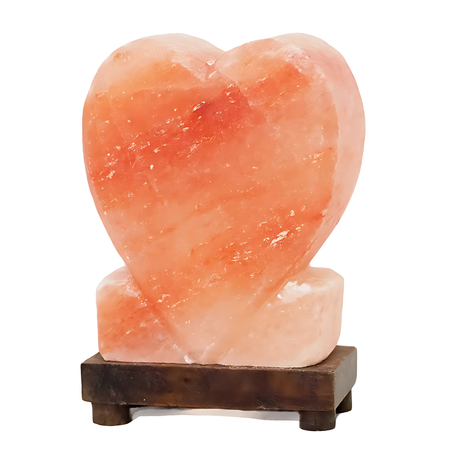 Upright heart-shaped Himalayan salt lamp with a timber base, glowing warmly in a cozy room.