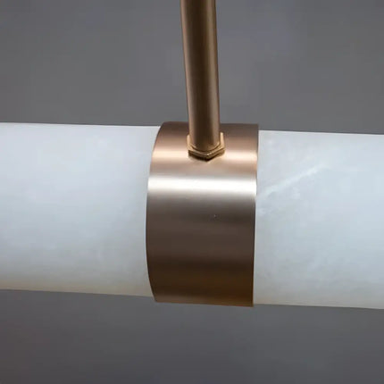 Close-up of a cylindrical light fixture with a bronze band on a gray background