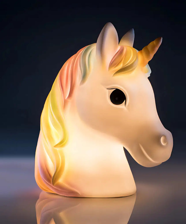 White unicorn LED lamp with a rainbow mane on a bedside table