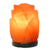 Rose-shaped Himalayan salt lamp with a timber base, glowing warmly in a cozy setting.