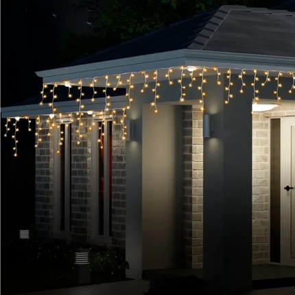 Illuminated icicle lights on a house with Solar 200 LED Icicle Lights in warm white color