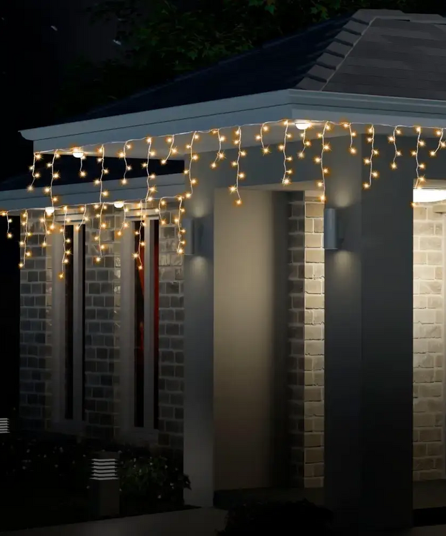Illuminated multicolor Solar 400 LED Icicle Lights decorating a house during nighttime