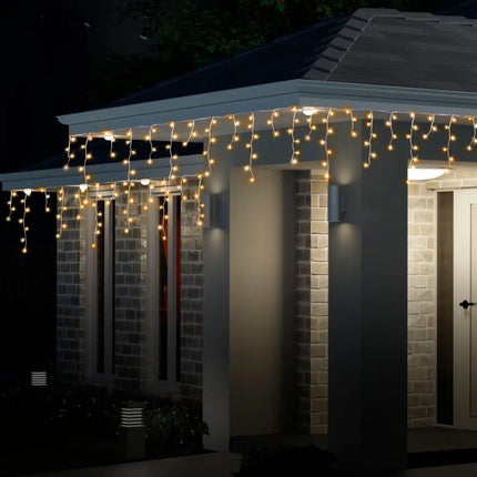 Illuminated icicle lights on a house showcasing Solar 400 LED Icicle Lights in Warm White